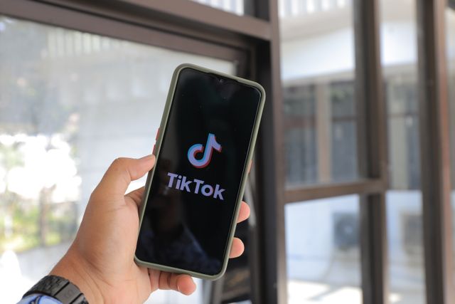 Hand holding a smartphone showing the TikTok app opening screen